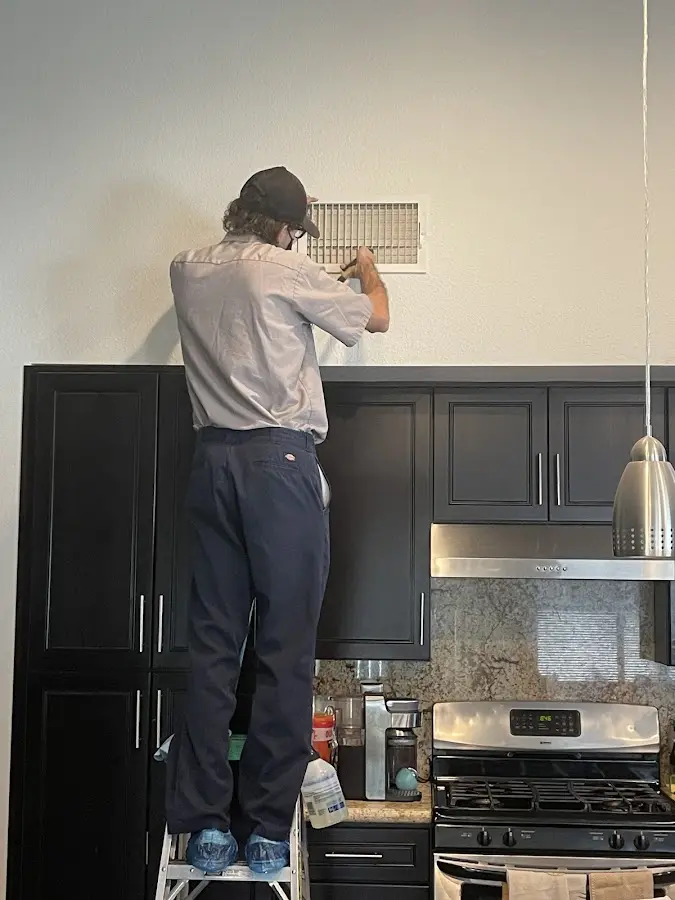 Technician inspecting an air vent during HVAC service in Burlingame